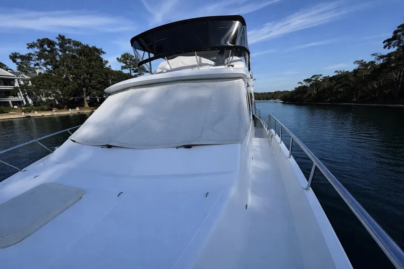 Slide: The Image of 2003 Altima 55 Pilothouse yacht docked by a serene waterway. - 3