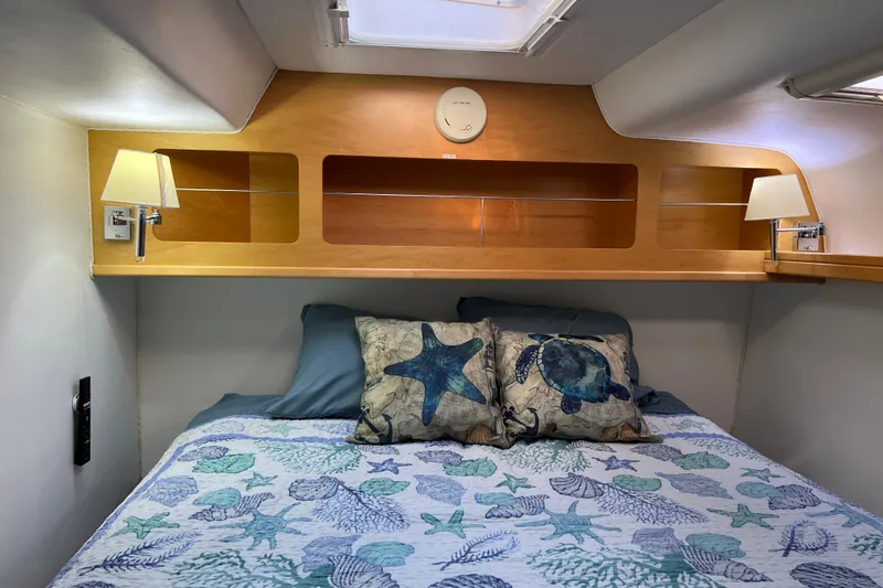 Slide: The Image of Cozy cabin interior of 2011 Privilege 495 yacht with nautical-themed bedding and wooden shelving. - 100