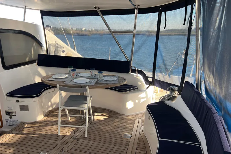 Slide: The Image of Outdoor dining area on 2011 Privilege 495 yacht with table and cushioned seating. - 46