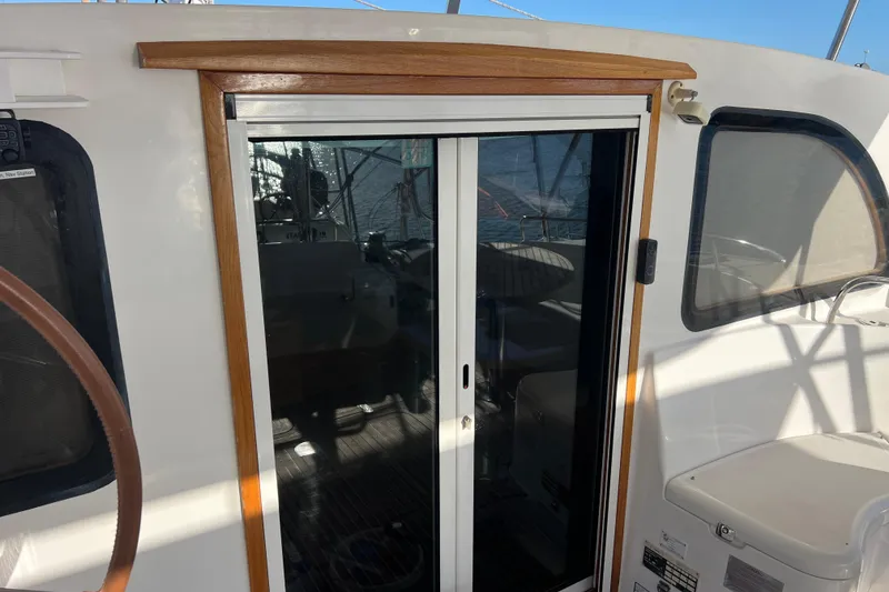 Slide: The Image of Sliding door on 2011 Privilege 495 yacht, featuring wooden trim and ocean reflection. - 48