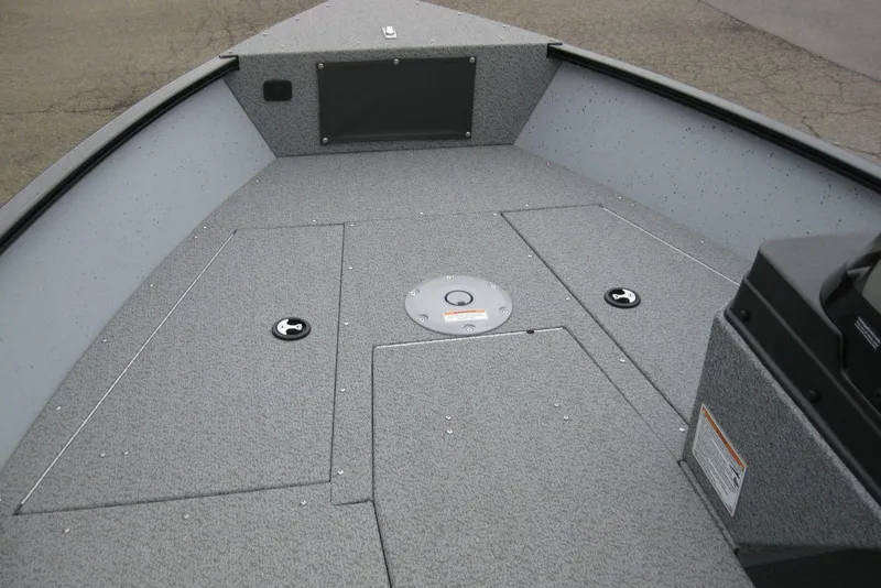 Slide: The Image of 2025 Lund 1775 Adventure SS boat interior with gray carpeted deck and storage compartments. - 12