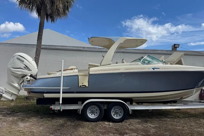Slide: The Image of 2020 Chris-Craft Launch 28 boat interior with beige seating, docked by a calm river. - 21