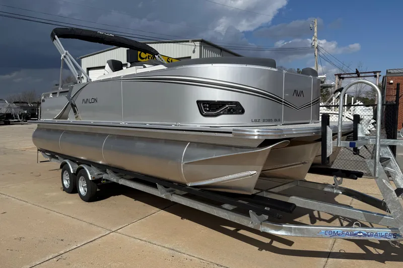 The Image of 2026 Avalon LSZ Quad Lounge Shift pontoon boat on trailer, parked outdoors. - 0