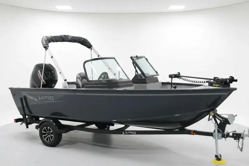 The Image of 2025 Lund 1775 Adventure Sport boat on trailer, sleek design, dark color, indoor setting. - 0