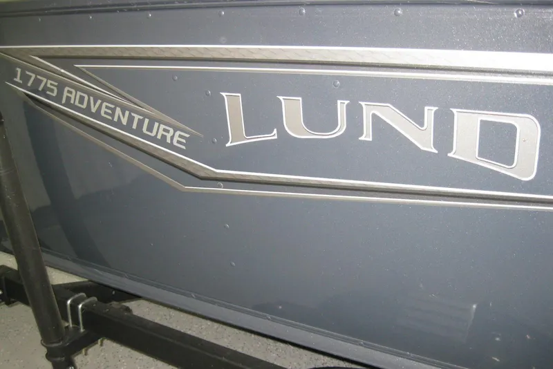 Slide: The Image of 2025 Lund 1775 Adventure Sport boat logo on a dark surface. - 2