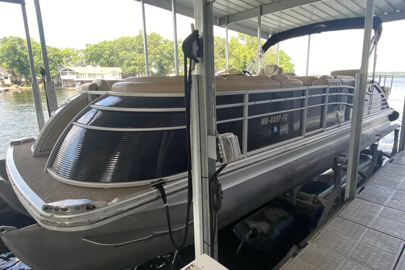 The Image of 2012 Bennington 2575 QCW I/O pontoon boat docked under a covered area. - 1