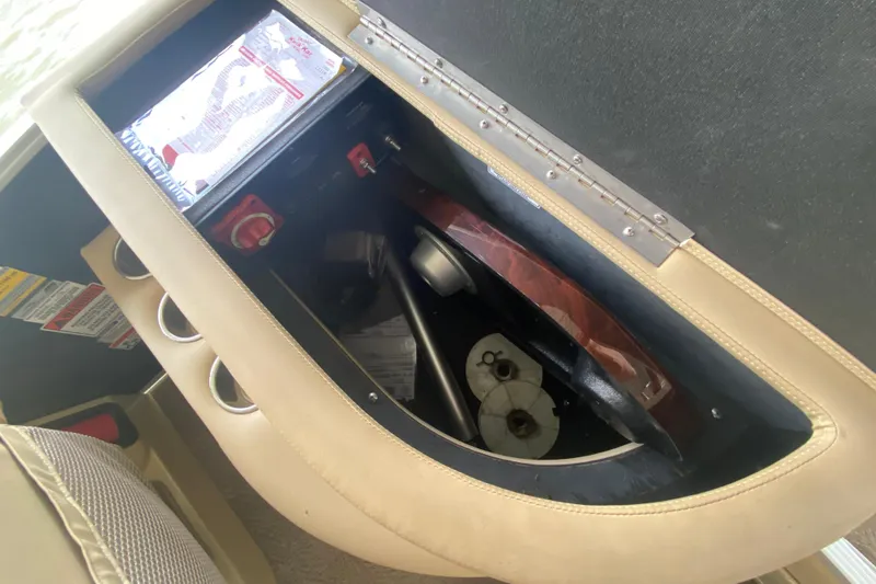 Slide: The Image of Storage compartment of a 2012 Bennington 2575 QCW I/O boat, featuring cup holders and safety instructions. - 14