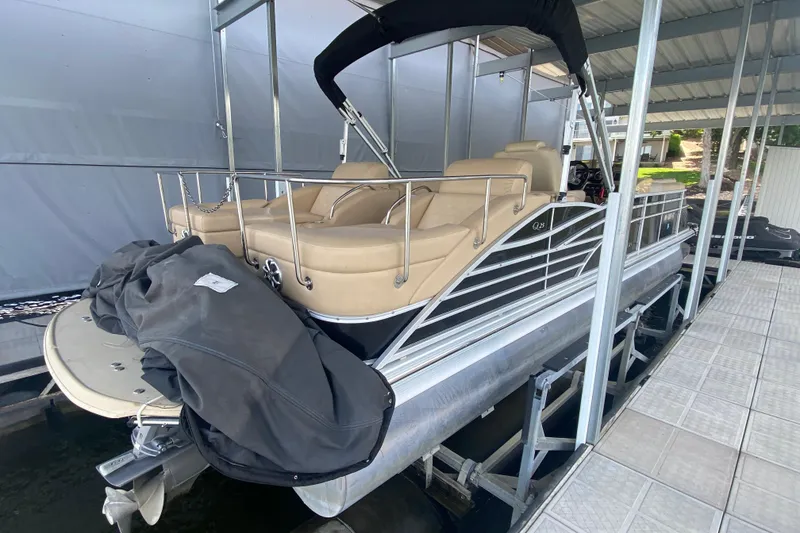 Slide: The Image of 2012 Bennington 2575 QCW I/O pontoon boat docked under a covered marina. - 3
