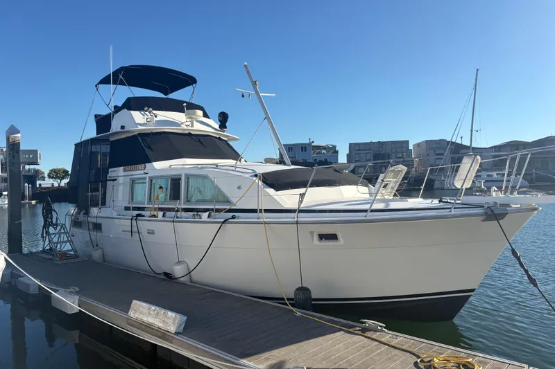 Slide: The Image of 1977 Bertram 42 Flybridge Motor Yacht docked in a marina under clear blue skies. - 1