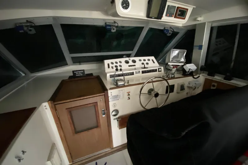 Slide: The Image of 1977 Bertram 42 Flybridge Motor Yacht helm with classic controls and steering wheel. - 14