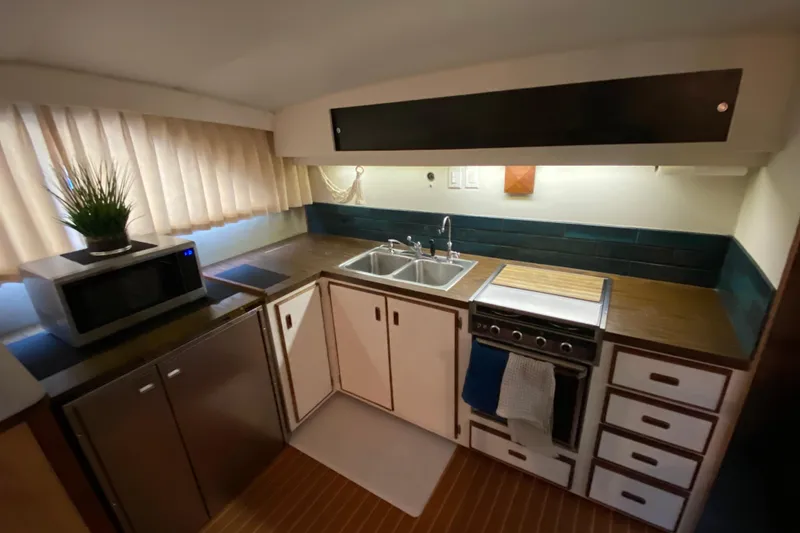 Slide: The Image of 1977 Bertram 42 Flybridge Motor Yacht kitchen with sink, stove, microwave, and cabinetry. - 17