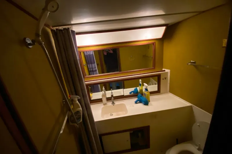 Slide: The Image of 1977 Bertram 42 Flybridge Motor Yacht bathroom with mirror, sink, and cleaning supplies. - 18