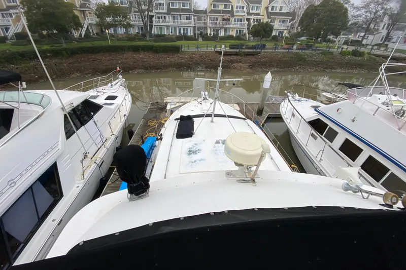 Slide: The Image of 1977 Bertram 42 Flybridge Motor Yacht docked between two boats in a marina. - 24