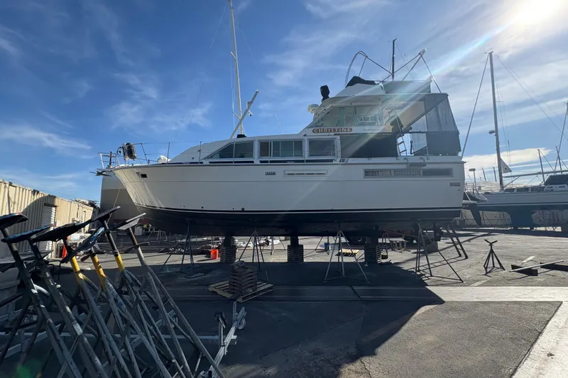 Slide: The Image of 1977 Bertram 42 Flybridge Motor Yacht on dry dock under clear blue sky. - 3