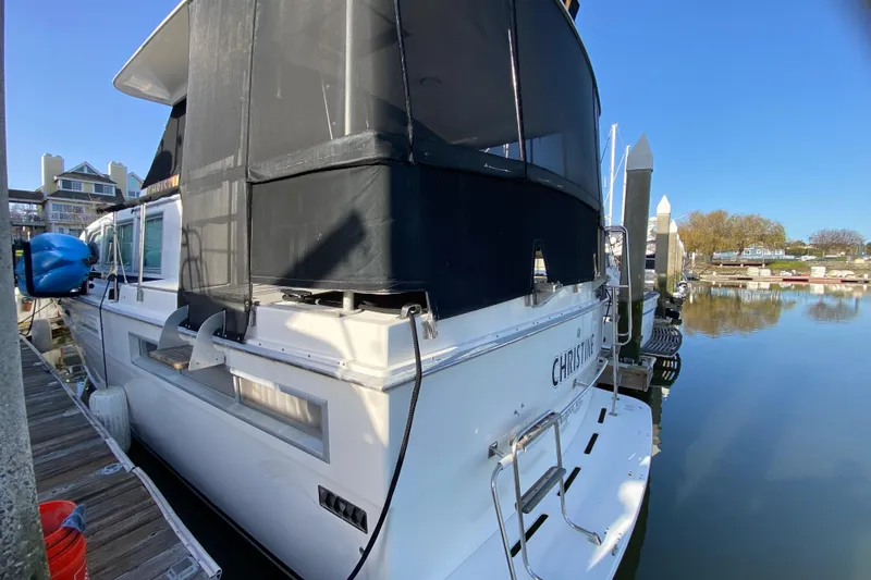 Slide: The Image of 1977 Bertram 42 Flybridge Motor Yacht docked at marina, rear view with covered flybridge. - 9