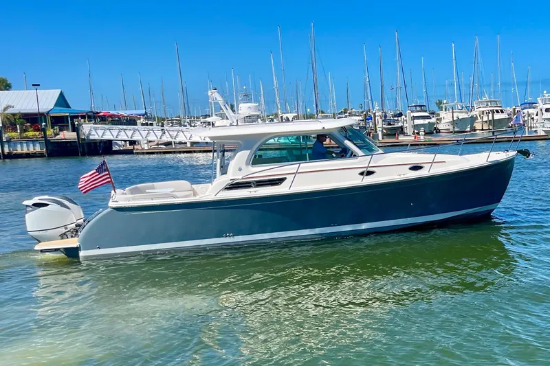 The Image of 2023 Back Cove 340 boat cruising in a marina with American flag. - 0