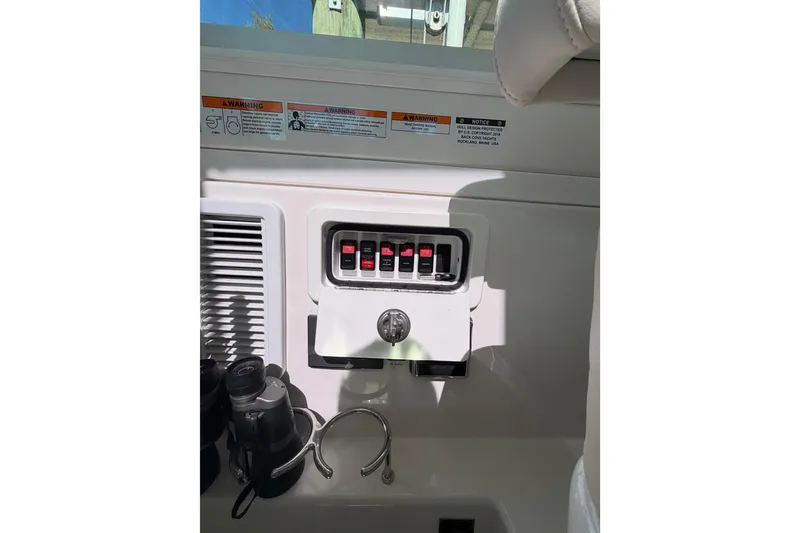 Slide: The Image of 2023 Back Cove 340 boat control panel with switches and warning labels. - 15