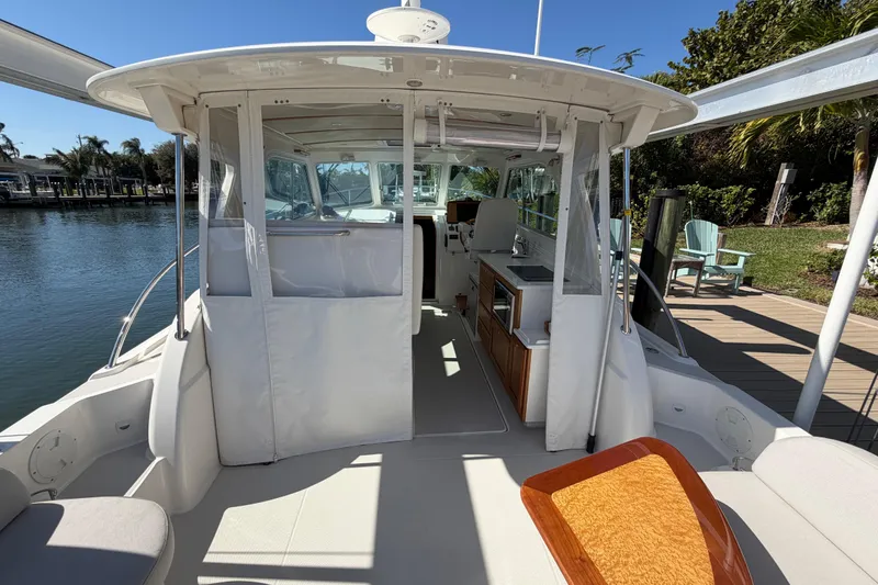 Slide: The Image of 2023 Back Cove 340 boat interior with seating and kitchen area, docked by water. - 24