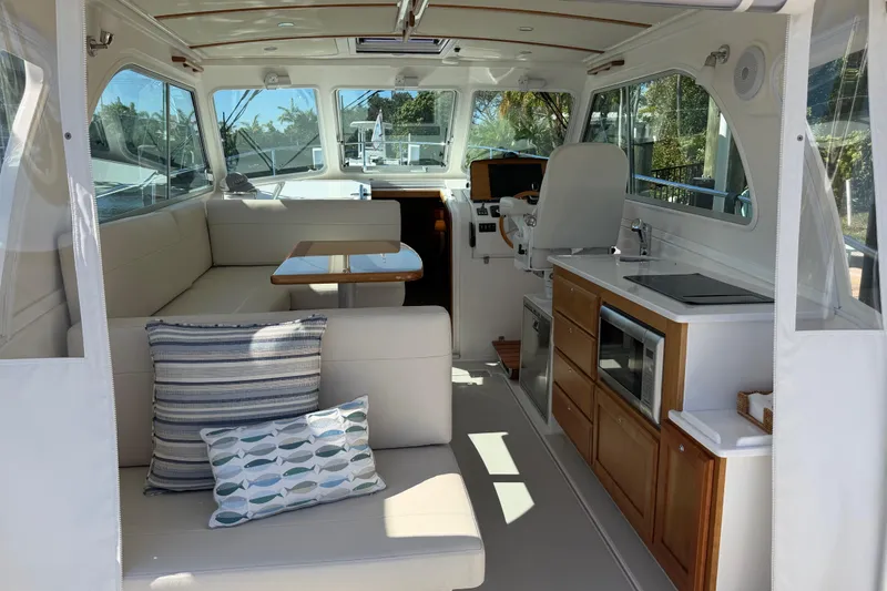 Slide: The Image of 2023 Back Cove 340 interior with seating, table, kitchenette, and helm station. - 26