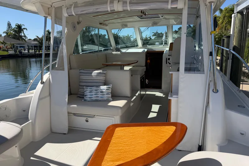 Slide: The Image of 2023 Back Cove 340 boat interior with seating, table, and cushions by the water. - 27