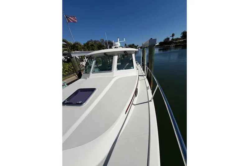 Slide: The Image of 2023 Back Cove 340 boat docked by serene waterfront under clear blue sky. - 33