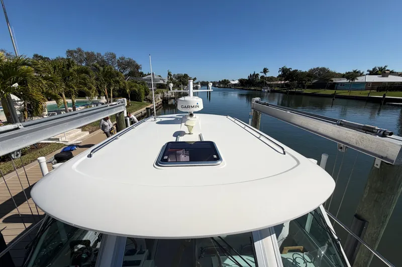 Slide: The Image of 2023 Back Cove 340 boat docked by a serene canal with clear blue skies. - 34