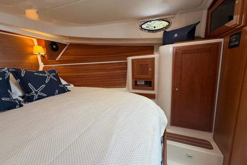 Slide: The Image of 2023 Back Cove 340 cabin interior with wood paneling and cozy bedding. - 7