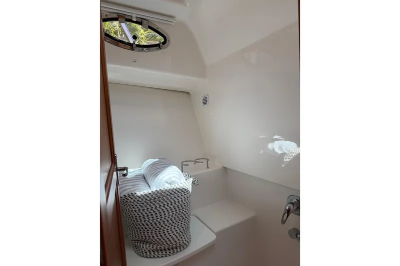 Slide: The Image of 2023 Back Cove 340 interior with porthole, featuring a cozy seating area and soft lighting. - 9
