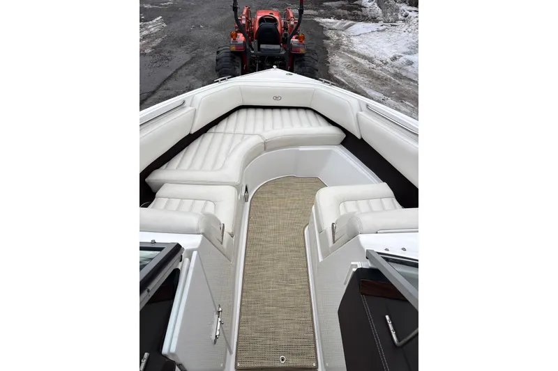Slide: The Image of 2015 Cobalt R5 boat interior with white seating and beige flooring, parked near a tractor. - 8