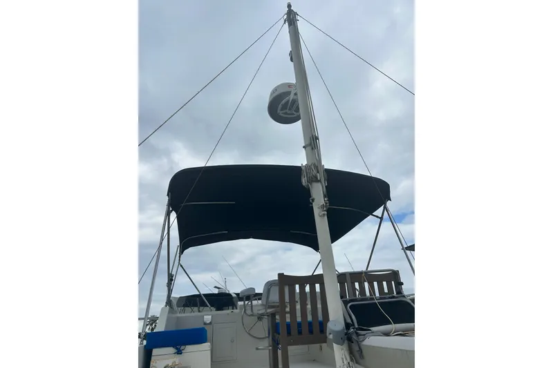 Slide: The Image of 2006 Mariner Orient sailboat with mast and canopy under cloudy sky. - 13