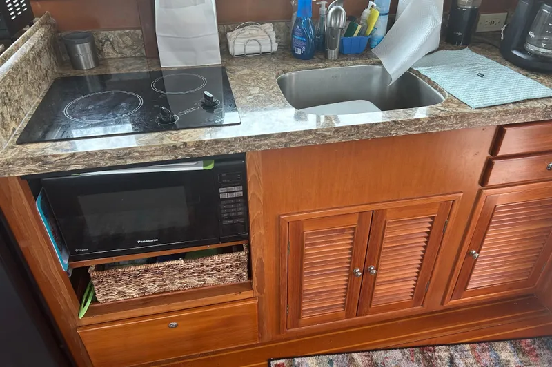 Slide: The Image of 2006 Mariner Orient kitchen with stove, sink, and microwave in wooden cabinetry. - 17