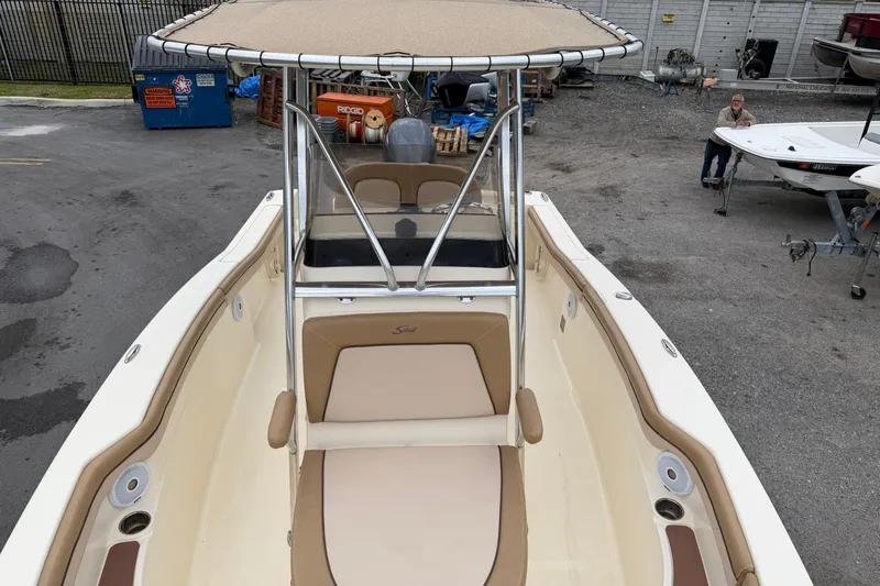 Slide: The Image of 2020 Scout 215 XSF boat with beige seating and T-top in a marina setting. - 13