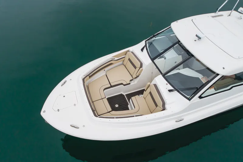 Slide: The Image of 2018 Pursuit boat with beige seating, white deck, and sleek design on calm water. - 10
