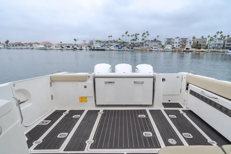 Slide: The Image of 2018 Pursuit boat deck with seating, overlooking a marina with palm trees and boats. - 26