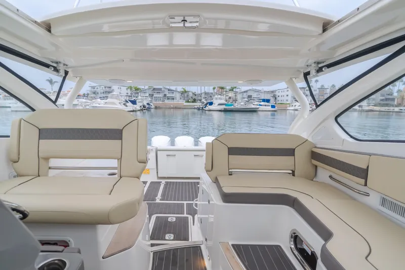 Slide: The Image of Interior of a 2018 Pursuit boat with beige seating, overlooking a marina. - 27
