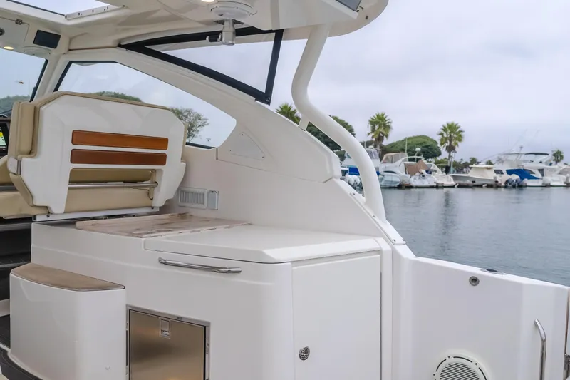 Slide: The Image of 2018 Pursuit boat interior with seating and storage, docked at a marina with palm trees. - 30
