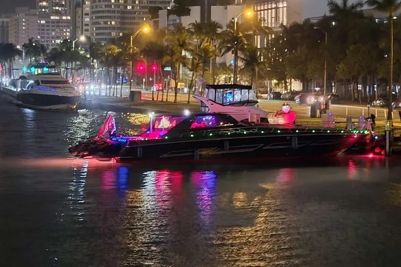 Slide: The Image of 1999 Sea Ray 630 Sundancer yacht with colorful lights docked at night in a city marina. - 10