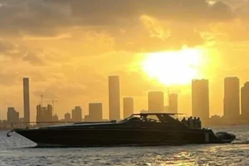 Slide: The Image of 1999 Sea Ray 630 Sundancer yacht cruising at sunset with city skyline backdrop. - 5