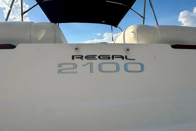 Slide: The Image of 2012 Regal 2100 Bowrider boat rear view with logo under blue sky. - 13