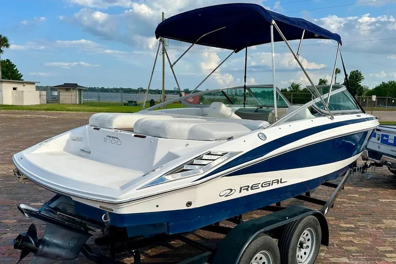 Slide: The Image of 2012 Regal 2100 Bowrider boat with blue and white design on trailer. - 4