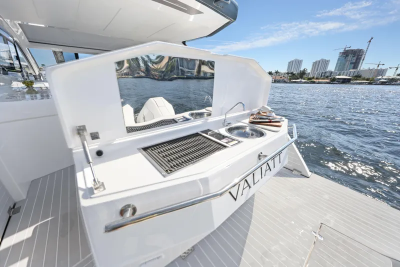 Slide: The Image of 2025 Valiatt 380 Bowrider boat with outdoor kitchen, docked by waterfront cityscape. - 6