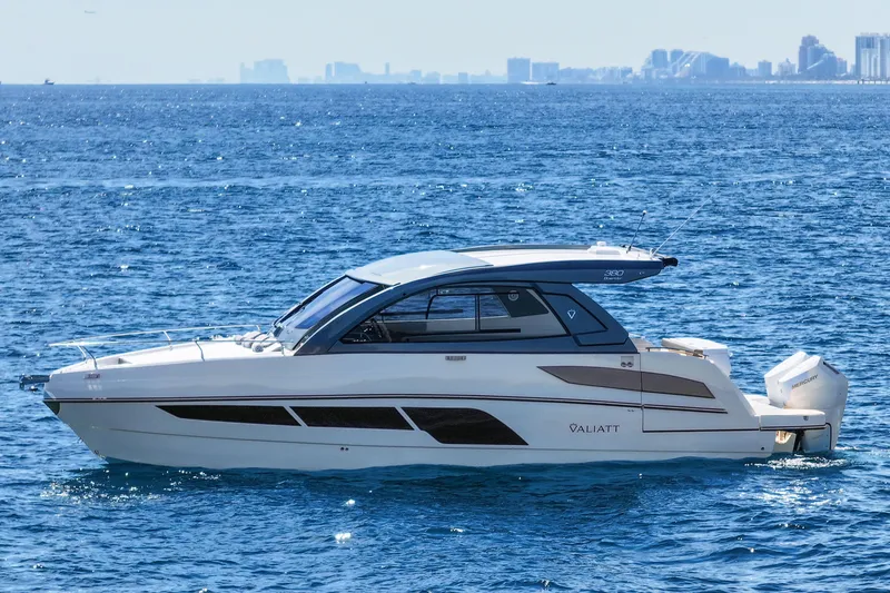Slide: The Image of 2025 VALIATT YACHTS 380 Bowrider cruising on open sea with city skyline in background. - 1