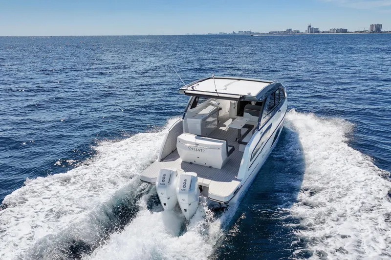 Slide: The Image of 2025 VALIATT YACHTS 380 Bowrider cruising on open sea with city skyline in background. - 27