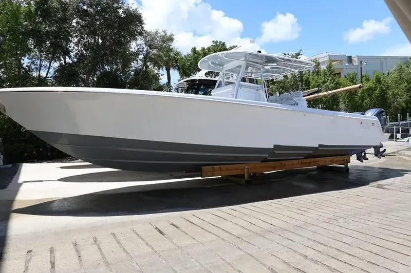 The Image of 2025 Contender 39 ST boat on trailer, surrounded by trees and buildings. - 1