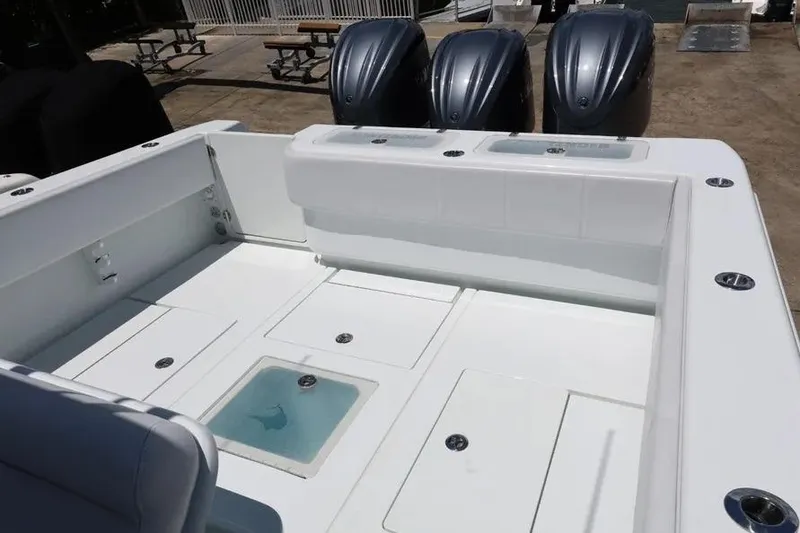 Slide: The Image of 2025 Contender 39 ST boat deck with triple outboard engines, featuring storage compartments. - 14