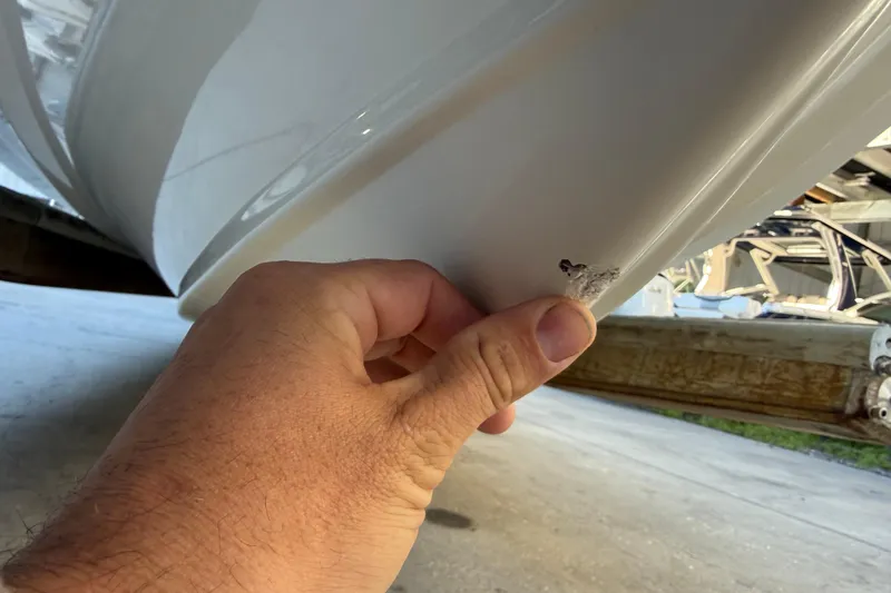 Slide: The Image of Hand inspecting damage on 2017 Mako 234 Center Console boat hull. - 14