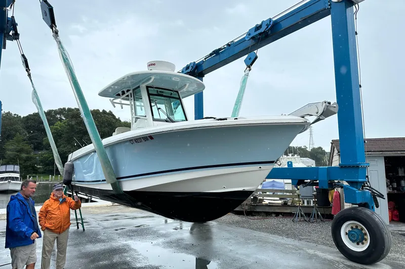 Slide: The Image of 2020 Boston Whaler 250 Outrage being lifted by a blue crane at a marina. - 2