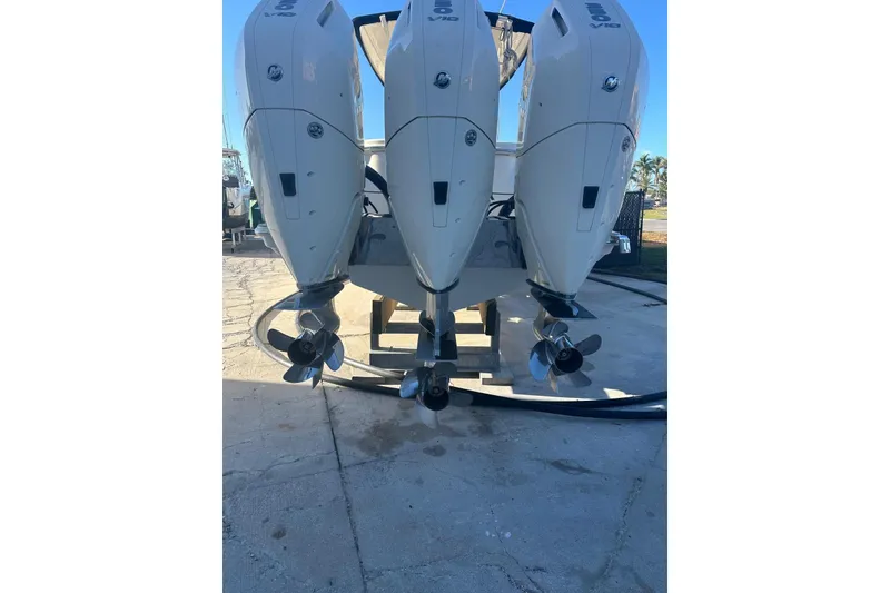 Slide: The Image of Triple outboard engines on a 2023 Scout 355 LXF boat, docked on concrete. - 3