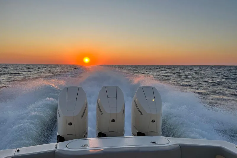 Slide: The Image of 2023 Scout 355 LXF boat cruising at sunset with powerful engines. - 4