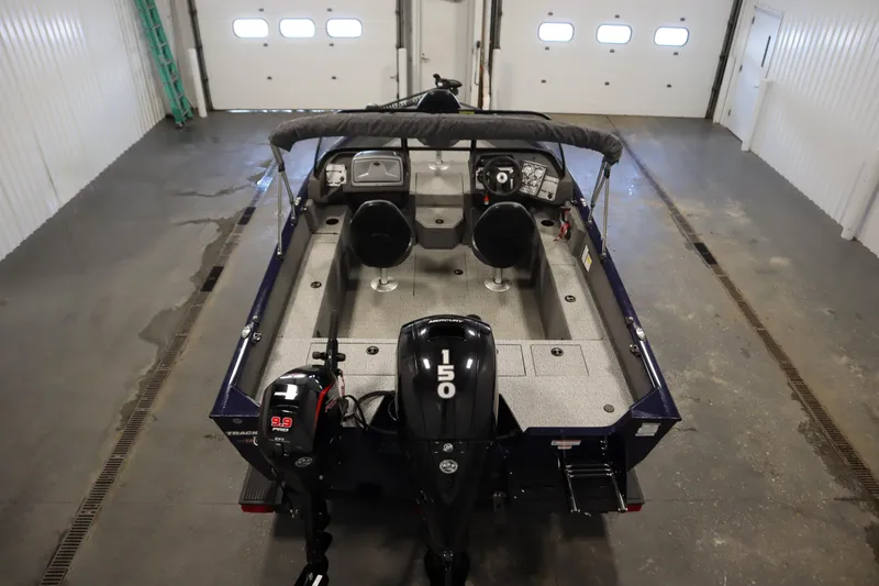 Slide: The Image of 2023 Tracker Pro Guide V-175 WT boat in garage, featuring dual motors and spacious interior. - 10